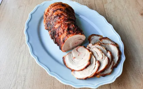 Soczysta rolada z boczku, pieczona do perfekcji, podana na błękitnej paterze. Idealna na rodzinny obiad.