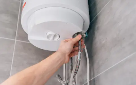 Mano che controlla i tubi di un scaldabagno a batteria non si accende.