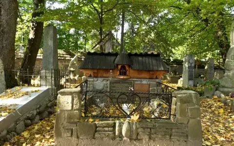 Cmentarz zasłużonych na Pęksowym Brzyzku. Kamienne nagrobki i krzyże toną w jesiennych liściach, tworząc zadumany krajobraz.