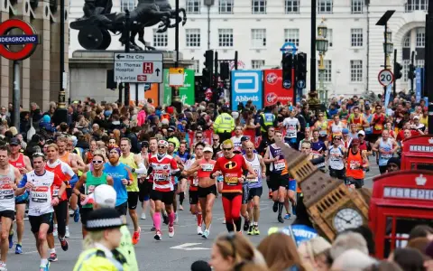 Corredores participan en el maratón de Londres, con Big Ben y cabinas telefónicas rojas de fondo.