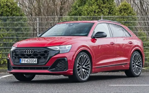 Czerwony Audi RS Q8 z czarnymi felgami stoi na parkingu.