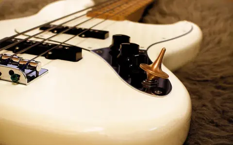 Ein weißes Bassmusikinstrument mit vier Saiten und einem bronzenen Kreisel auf dem Bedienfeld.