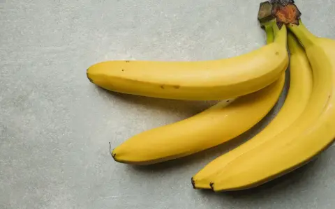 Kilka żółtych bananów leżących na szarym tle.