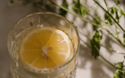 Ett glas med vatten och en citronskiva, perfekt för varma sommardagar. Enkel och uppfriskande bland sommar drinkar.
