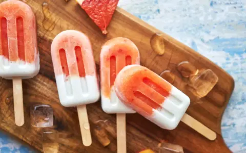 Erfrischendes Erdbeereis auf Holzbrett, mit Eiswürfeln und Grapefruitstücken. Perfekt für heiße Tage, wenn man Kalorien im Blick behält.