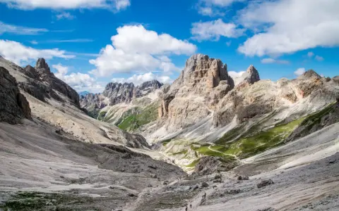 Malownicze **Val di Fassa** w Dolomitach. Kręta ścieżka prowadzi przez skaliste zbocza i zielone hale ku majestatycznym szczytom.