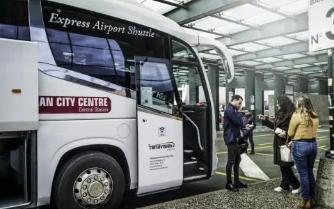 Autobus Express Airport Shuttle z napisem "AN CITY CENTRE Central Station" czeka na pasażerów. Podróż z Mediolan Malpensa do centrum jest prosta.