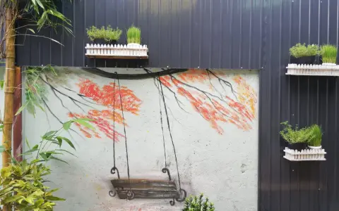 Un columpio pintado en un muro, ideal para inspirar al pintar patios pequeños. Las ramas anaranjadas y el bambú añaden color.