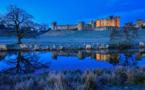 Un château majestueux se reflète dans l'eau calme, sous un ciel d'un bleu profond. Une scène paisible de **heure bleue photo**.