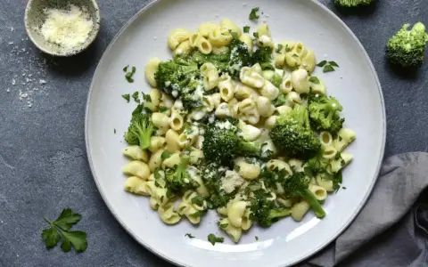 Pasta con brócoli cremosa, espolvoreada con queso rallado y perejil fresco. Un plato sencillo y delicioso.