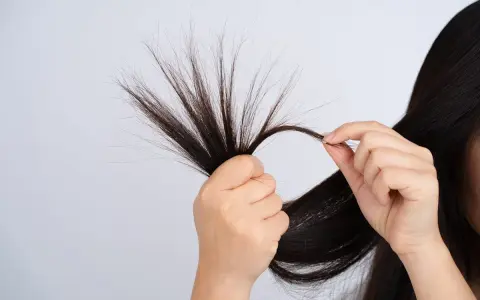 Mani che esaminano ciocche di capelli fini che si spezzano, mostrando la fragilità e la necessità di cura.