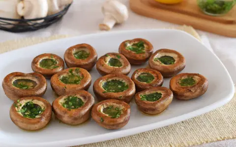 Champiñones a la plancha, dorados y rellenos de perejil fresco, listos para disfrutar.