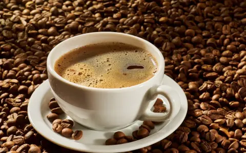 A white cup of coffee sits on a saucer surrounded by roasted coffee beans. Czy kawa rozpuszczalna podnosi ciśnienie?
