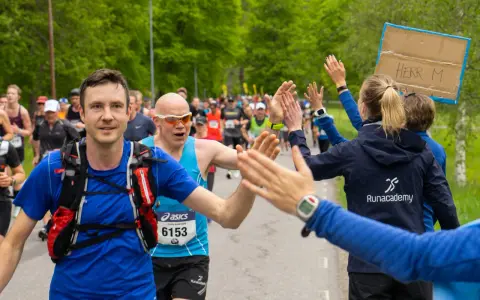 Glada löpare ger high-fives under loppet. Sista veckan innan halvmarathon, peppas deltagarna av publiken.