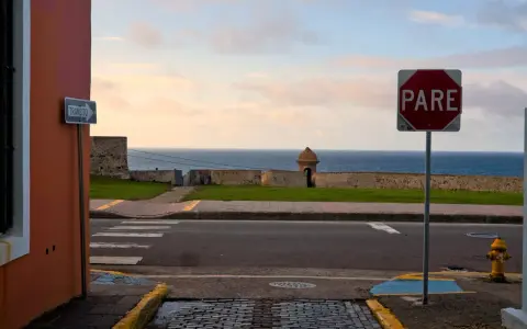 A "PARE" sign stands by the ocean in Puerto Rico. Should I rent a car to explore this beautiful island?