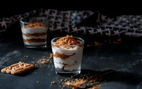 Deux verrines de tiramisu speculoos, garnies de miettes croustillantes. Un biscuit speculoos repose à côté.