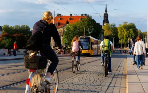 Menschen radeln durch eine Stadt in Deutschland, ein gelber Tram fährt vorbei. Perfekt für Bikepacking Deutschland!
