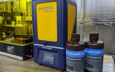 Dwa drukarki 3D Anycubic, w tym Anycubic Photon Mono SE, oraz butelki z żywicą do druku.