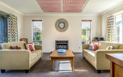 Sala de estar con sofás, chimenea y un moderno techo radiante con patrón de espiral roja.