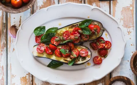 Melanzane ripiene vegetariane con pomodorini, basilico e semi di zucca, un piatto colorato e saporito.