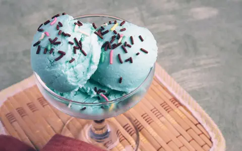Ein Glas mit drei Kugeln blaues Eis, bestreut mit Schokostreuseln und bunten Zuckerstreuseln.