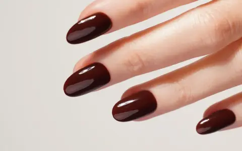 Une idée manucure automne : des ongles courts et arrondis, vernis d'un brun chocolat profond et brillant, évoquant la douceur des feuilles mortes.