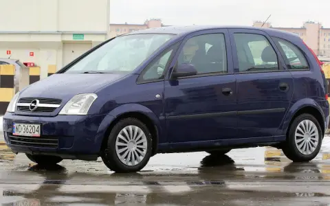 Granatowy Opel Meriva na mokrej nawierzchni. Kierowca w okularach. Wiele pozytywnych opinii o tym modelu.