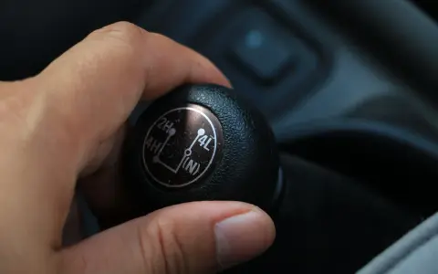 Dłoń ustawia dźwignię na 4L, aktywując napęd 4x4 dołączany ręcznie, gotowy na trudny teren.