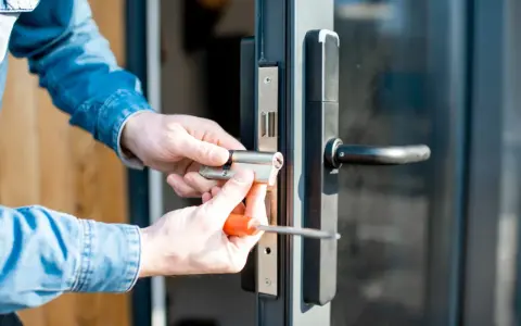 Mani che sostituiscono serratura porta con cacciavite.