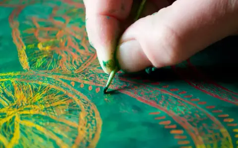Main d'un artiste peintre travaillant sur une peinture à l'huile aux couleurs vives.