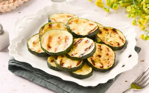 Rodajas de calabacín a la plancha, tiernas y con marcas de parrilla, servidas en un plato blanco.