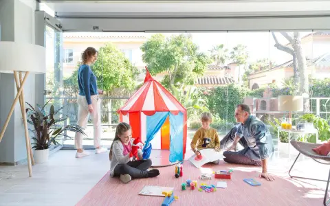 Familia divirtiéndose en una terraza decorada para niños con una carpa de circo y juegos.
