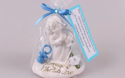 Figurka aniołka z niebieskim smoczkiem i różą, ozdobiona wstążką, z metryczką.