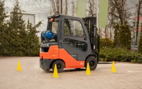 Pomarańczowy wózek widłowy Toyota na placu manewrowym. Idealne miejsce na kurs na wózek widłowy Kraków.