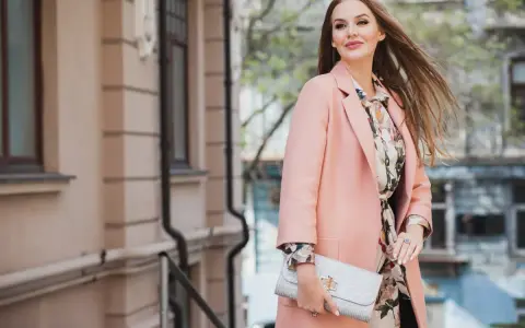 Donna con cappotto rosa e abito floreale, perfetta idea su come vestirsi per una comunione.