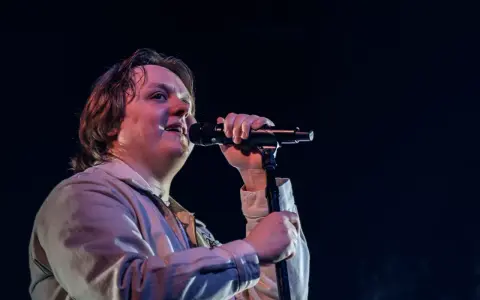 Lewis Capaldi sjunger passionerat på scen i Sverige, med mikrofonen i handen och blicken uppåt.