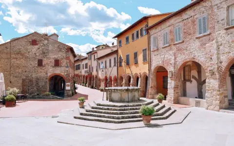 Piazza con pozzo antico e case in pietra e intonaco colorato, un assaggio di cosa vedere a Civitella in Val di Chiana.