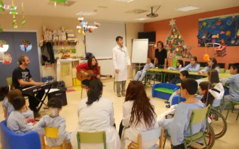 Niños y adultos participan en estaciones de aprendizaje, con música y actividades creativas.