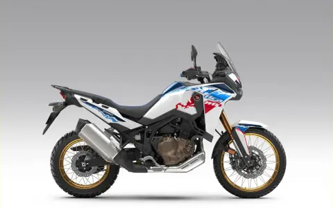 Nowy motocykl Honda Africa Twin 1100 w białym malowaniu z niebieskimi i czerwonymi akcentami, gotowy na przygodę.