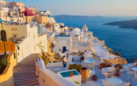 Piękne białe domy na Santorini, idealna pogoda na wrzesień w Grecji. Widok na błękitne morze i kalderę.