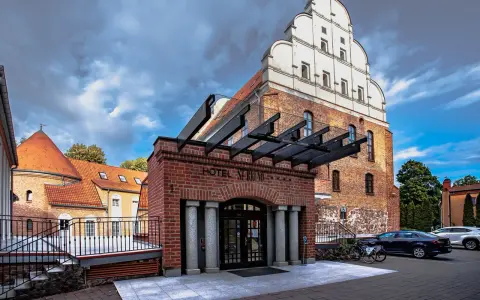 Hotel St. Bruno w Giżycku, dawniej zamek krzyżacki, z charakterystyczną ceglaną fasadą i białym szczytem.