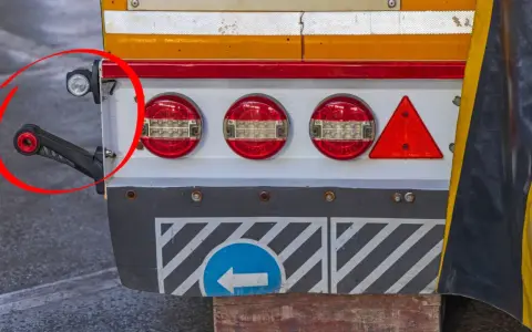 Detalle de la parte trasera de un camión, mostrando luces de galibo, reflectores y un brazo de soporte.