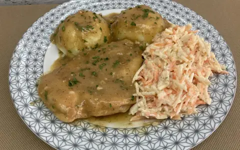 Pyszna pierś z kurczaka w sosie własnym, podana z purée ziemniaczanym i surówką z marchewki i kapusty.