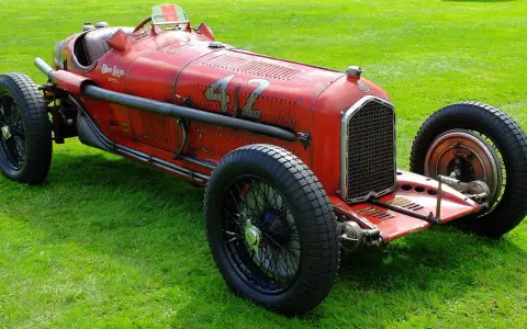 Roter Alfa Romeo P3 Rennwagen mit Nummer 42 fährt auf einer Straße, Fahrer mit Kopftuch.