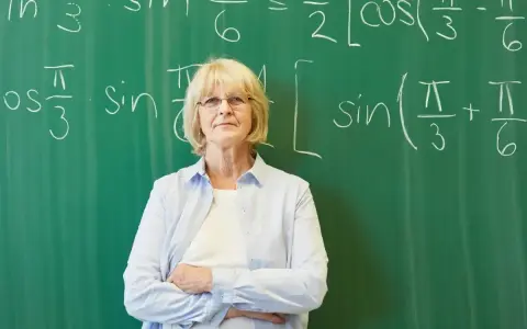 Nauczycielka matematyki przed tablicą z równaniami. Zatrudnienie nauczyciela po 1 września do kiedy umowa?