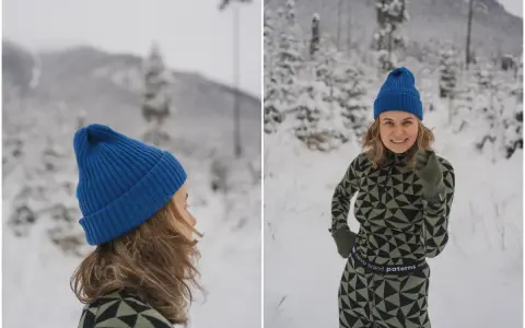 Uśmiechnięta kobieta w zimowym krajobrazie, ubrana w komplet z wełny merino. Jej strój podkreśla właściwości tej naturalnej tkaniny: ciepło i komfort.