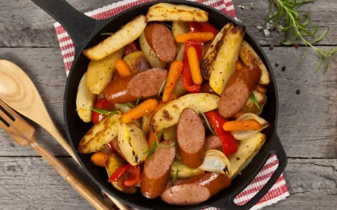 Stare przepisy na obiad: kiełbasa z ziemniakami, marchewką i papryką zapiekane w żeliwnej patelni.