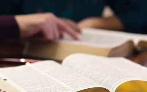 Hände studieren die Bibel, ein Symbol für tiefen Glauben und spirituelle Suche.