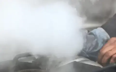 Sale humo del motor y huele a quemado. Una mano con un trapo intenta arreglar la avería.