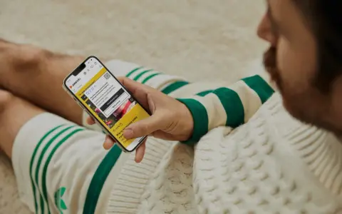 Mężczyzna sprawdza na telefonie, czy zalando jest legit, przeglądając aplikację z poradami stylistycznymi.